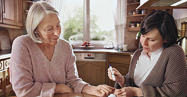 Nachweis der Elterneigenschaft für die Pflegeversicherung: Tochter mit pflegebedürftiger Mutter in einer Küche. Nachweis der Elterneigenschaft für die Pflegeversicherung: Tochter mit pflegebedürftiger Mutter in einer Küche.