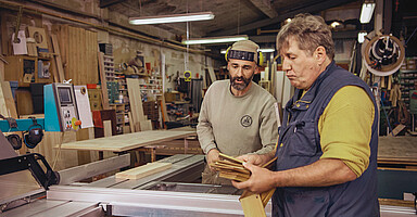 Online-Seminar „Personaleinsatz bei anderen Arbeitgebern“: Zwei Männer besprechen sich in einer Werkstatt. Online-Seminar „Personaleinsatz bei anderen Arbeitgebern“: Zwei Männer besprechen sich in einer Werkstatt.