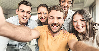 Eine Gruppe von jungen Beschäftigten macht ein Selfie