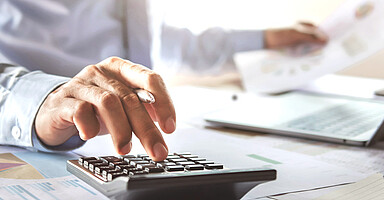 Online-Seminar „Praxistipps für die Entgeltabrechnung“: Mann am Schreibtisch tippt auf einem Taschenrechner Online-Seminar „Praxistipps für die Entgeltabrechnung“: Mann am Schreibtisch tippt auf einem Taschenrechner