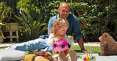 Nachweis von Kindern für die Pflegeversicherung: Vater mit Tochter spielen im Garten