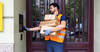 Basisarbeitende wertschätzen: Paketlieferant klingelt an einem Wohnhaus Basisarbeitende wertschätzen: Paketlieferant klingelt an einem Wohnhaus