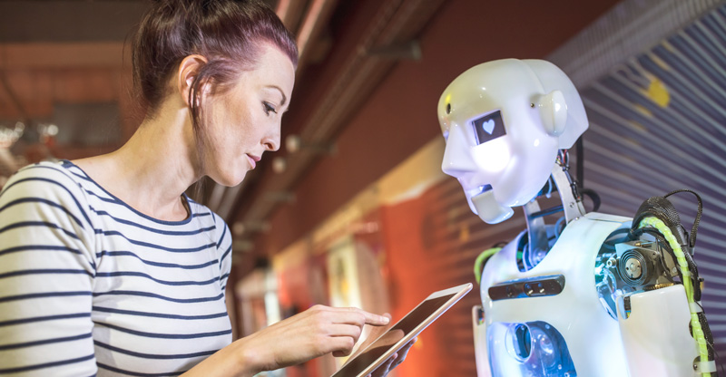 KI und Arbeit: Frau mit Tablet vor einem humanoiden Roboter KI und Arbeit: Frau mit Tablet vor einem humanoiden Roboter