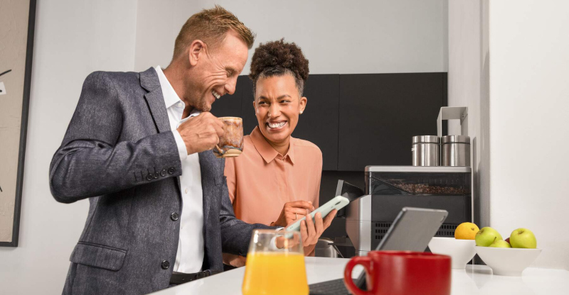 AOK atWork: Zwei Menschen schauen in einer Büroküche gemeinsam auf ein Smartphone, umgeben von gesunden Lebensmitteln AOK atWork: Zwei Menschen schauen in einer Büroküche gemeinsam auf ein Smartphone, umgeben von gesunden Lebensmitteln