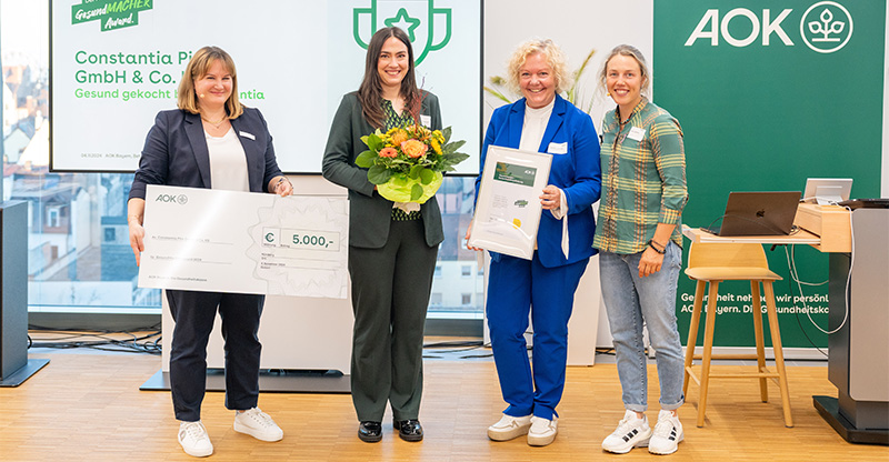 Preisverleihung „GesundMACHER Award“: Eine Gruppe von Frauen präsentiert einen Gewinnerscheck