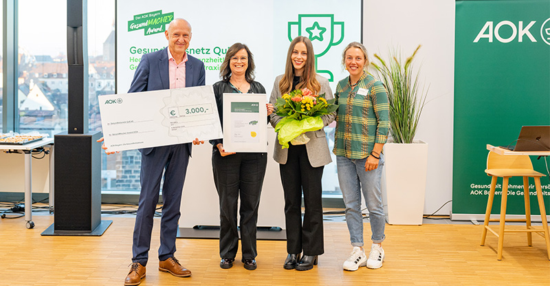 Preisverleihung „GesundMACHER Award“: Eine Gruppe von Personen präsentiert einen Gewinnerscheck