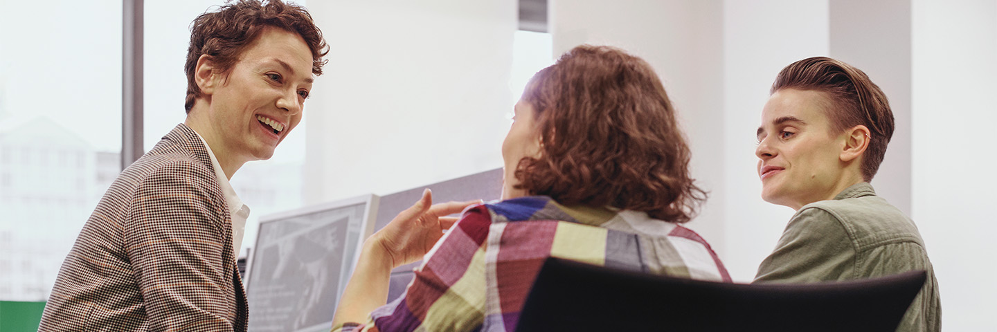 Positiv führen: Drei Menschen sitzen gut gelaunt in einer Besprechung