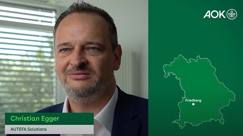 Christian Egger von AUTEFA Solutions spricht in einem Interview, daneben eine Karte von Bayern mit Markierung auf Friedberg, AOK-Logo oben rechts.