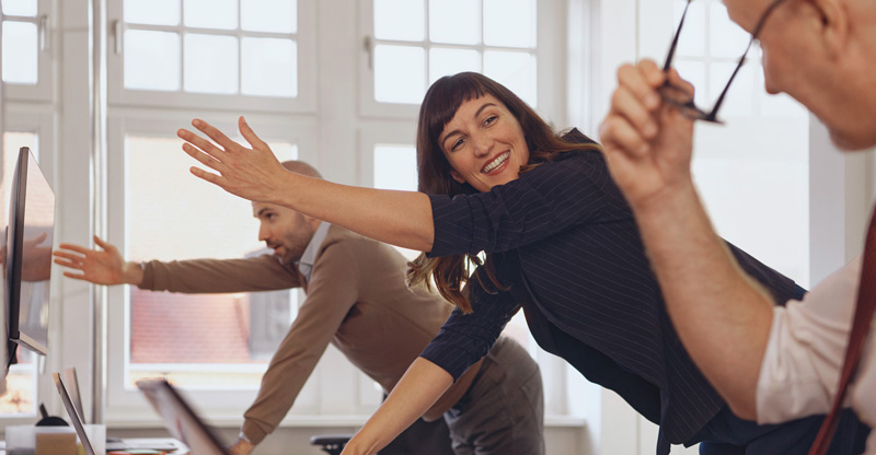 Drei Menschen machen Gymnastik im Büro