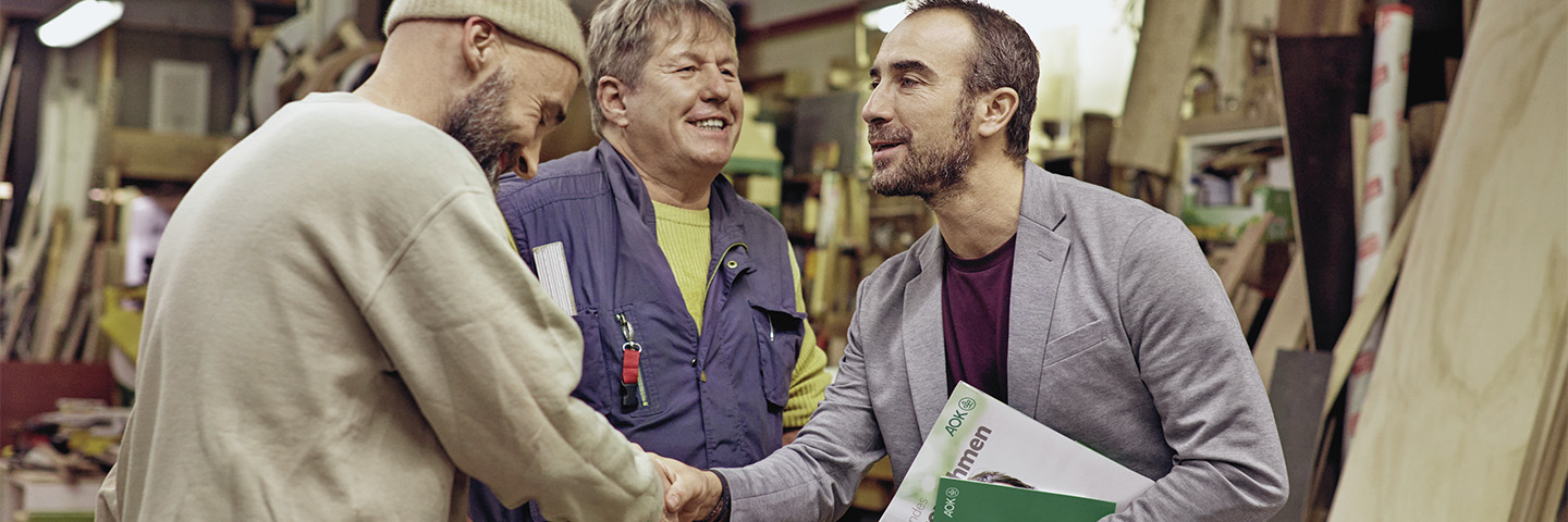 Drei Männer arbeiten gemeinsam in einer Werkstatt