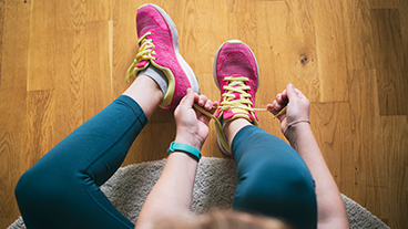 Fordere dich sportlich heraus Eine Person bindet sich ihre Sportschuhe zusammen.