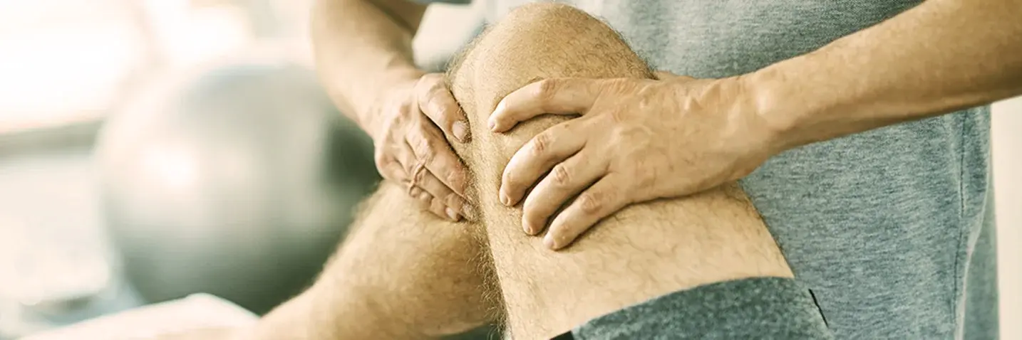 Therapeut behandelt Knie eines Patienten