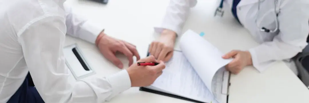 Patient unterschreibt Dokumente in Arztpraxis (Symbolbild)