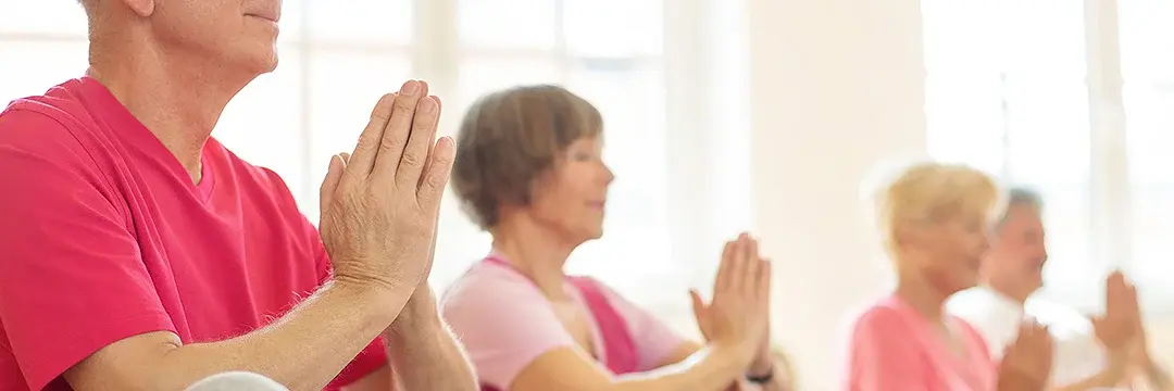 Ältere Menschen meditieren in Yoga-Kurs