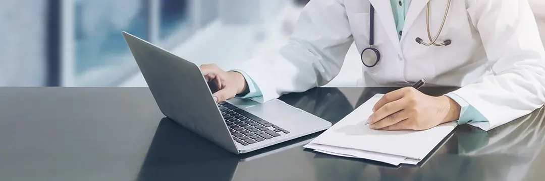 Arzt arbeitet am Schreibtisch mit Computer (Symbolbild)