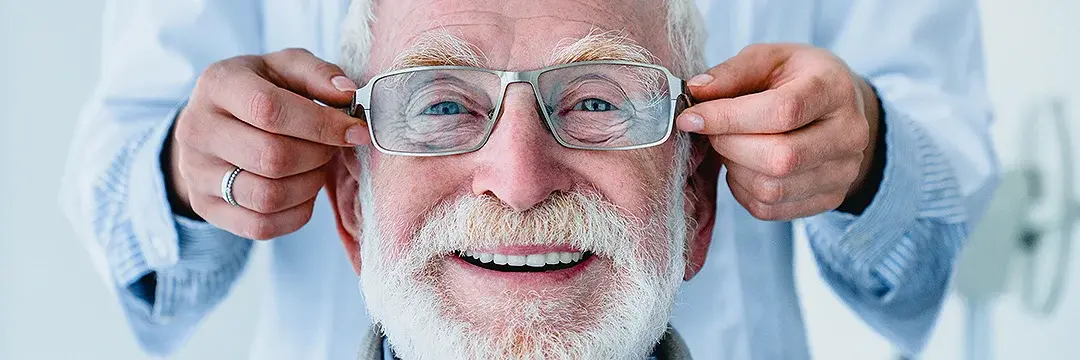 Optiker passt älterem Mann eine Brille an Optiker passt älterem Mann eine Brille an