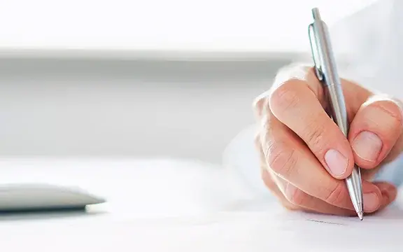 Arzt hält einen Stift in der Hand und schreibt eine Verordung oder Rezept