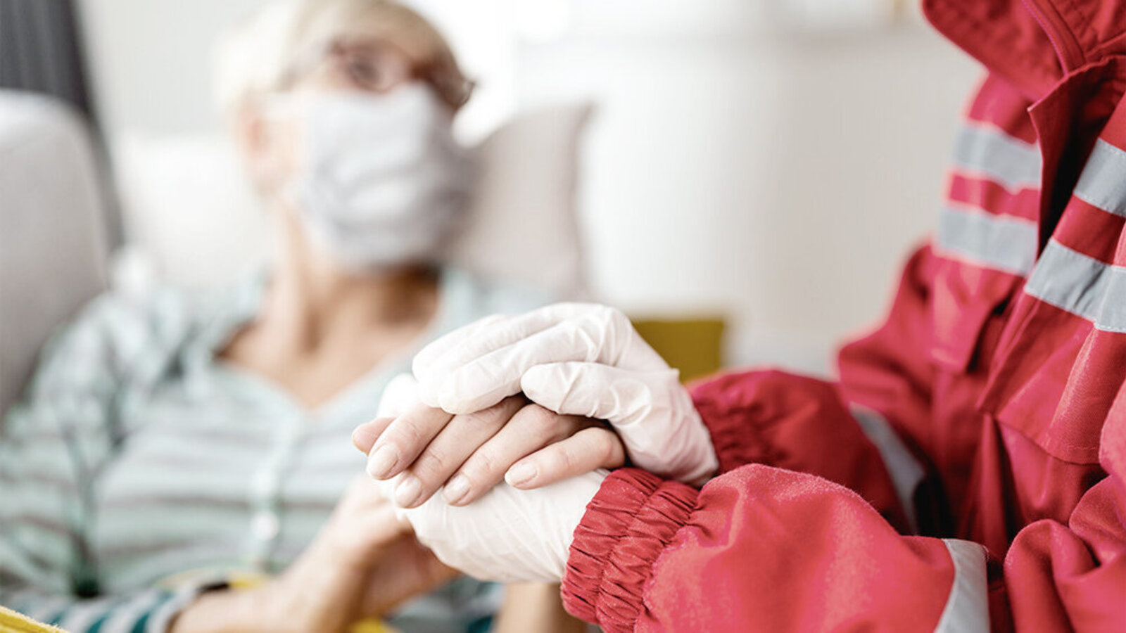 Rettungssanitäter hält die Hand einer älteren Frau