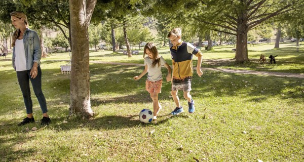 Mädchen und Junge rennen gemeinsam durch einen Park.