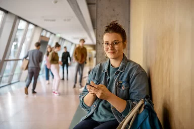 Eine Studentin wartet vor einem Hörsaal. Die AOK sorgt beim Auslandsstudium für den Versicherungsschutz.