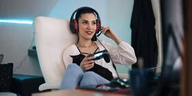 Frau sitzt mit Headset auf einem Sessel und spielt ein Videospiel.