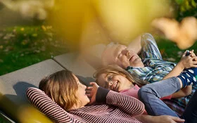 Zwei Kinder und ein älterer Mann liegen in der Sonne. Mit dem Familiencoach Krebs können sie gemeinsam besser mit der Krebserkrankung umgehen.
