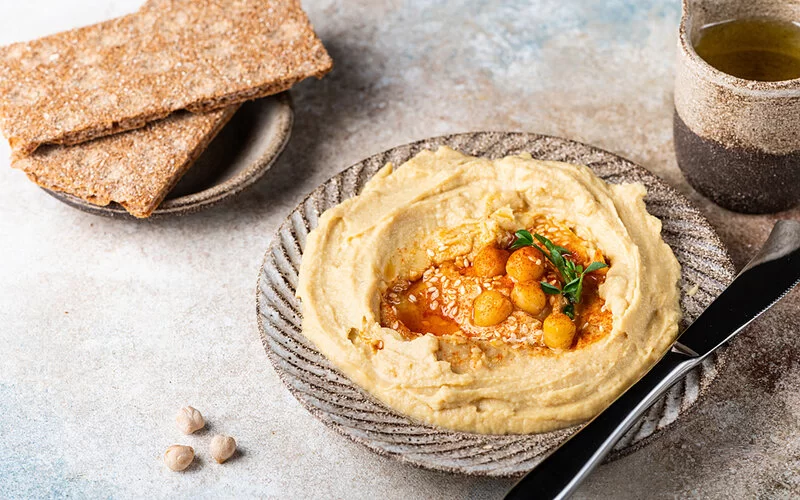 Hummus und Knäckebrot nebeneinander angerichtet.