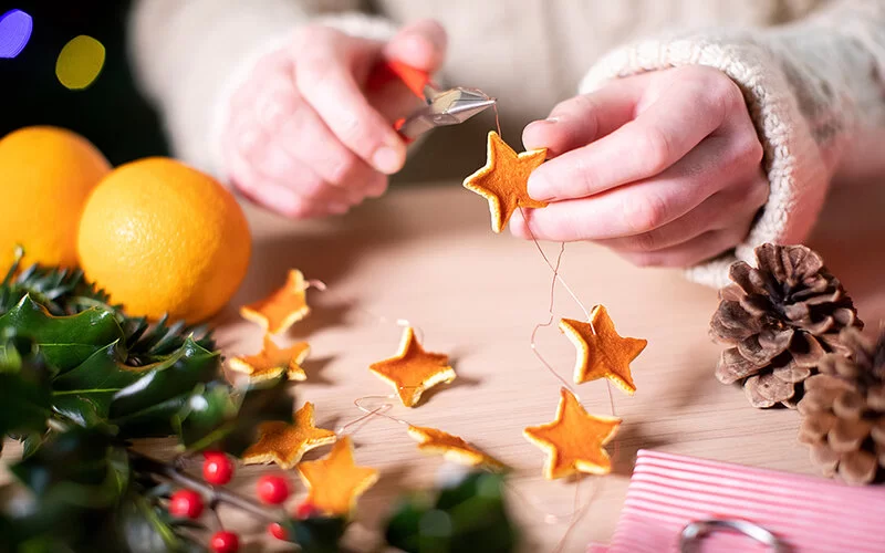 Hände fügen mit Hilfe einer Zange Weihnachtssterne zusammen.