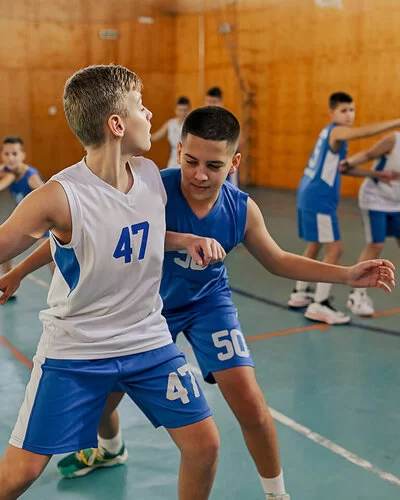 Mehrere Jungen einer Basketball-Mannschaft trainieren in einer Halle.