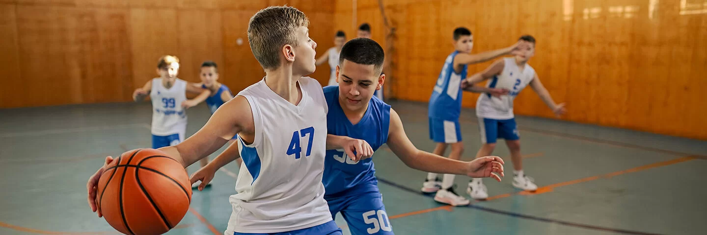 Mehrere Jungen einer Basketball-Mannschaft trainieren in einer Halle.