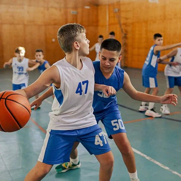 Mehrere Jungen einer Basketball-Mannschaft trainieren in einer Halle.