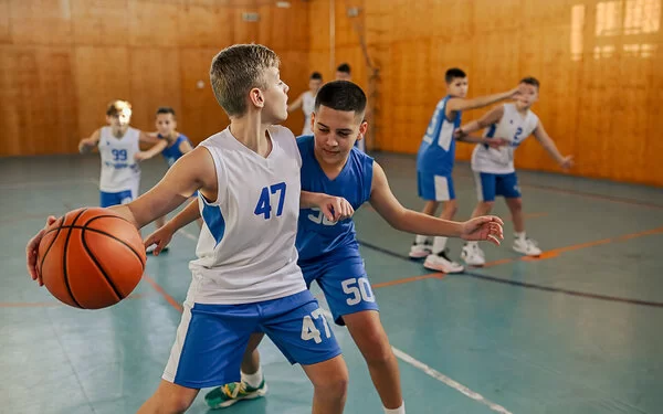 Mehrere Jungen einer Basketball-Mannschaft trainieren in einer Halle.