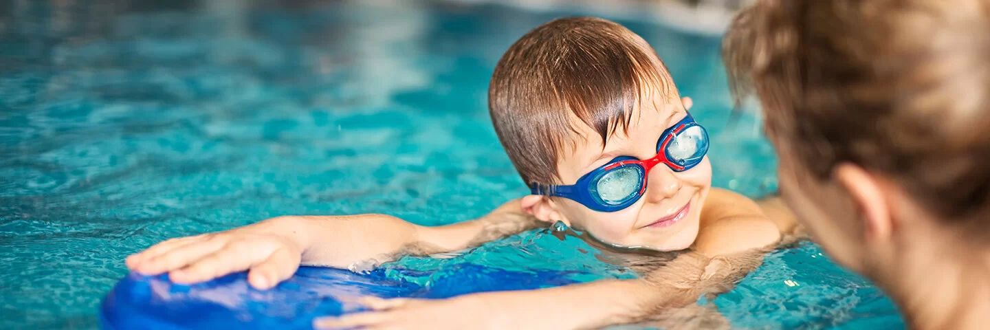 Kleiner Junge beim Schwimmunterricht im Hallenbad.