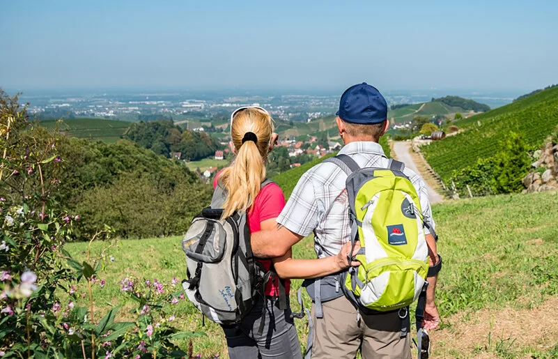 Ein Paar mit Rucksäcken genießt einen Spaziergang im Naturpark Schwarzwald, die Aussicht ist atemberaubend und einladend.