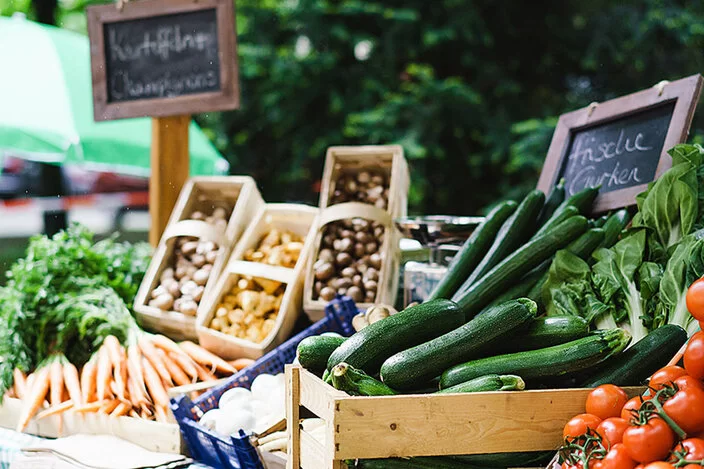 Frisches Gemüse wie Zucchini, Tomaten und Möhren auf einem Marktstand.