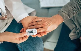 Eine Ärztin misst mit einem Pulsoxymeter am Finger einer Patientin die Sauerstoffsättigung des Blutes.