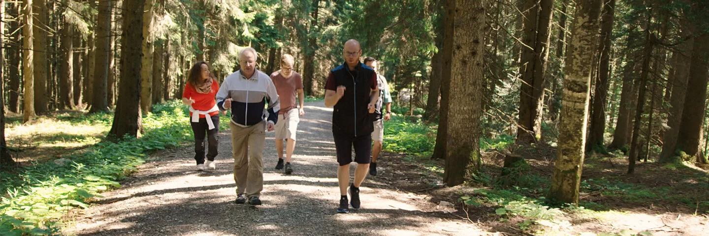 Eine Gruppe älterer Menschen läuft durch einen Wald.