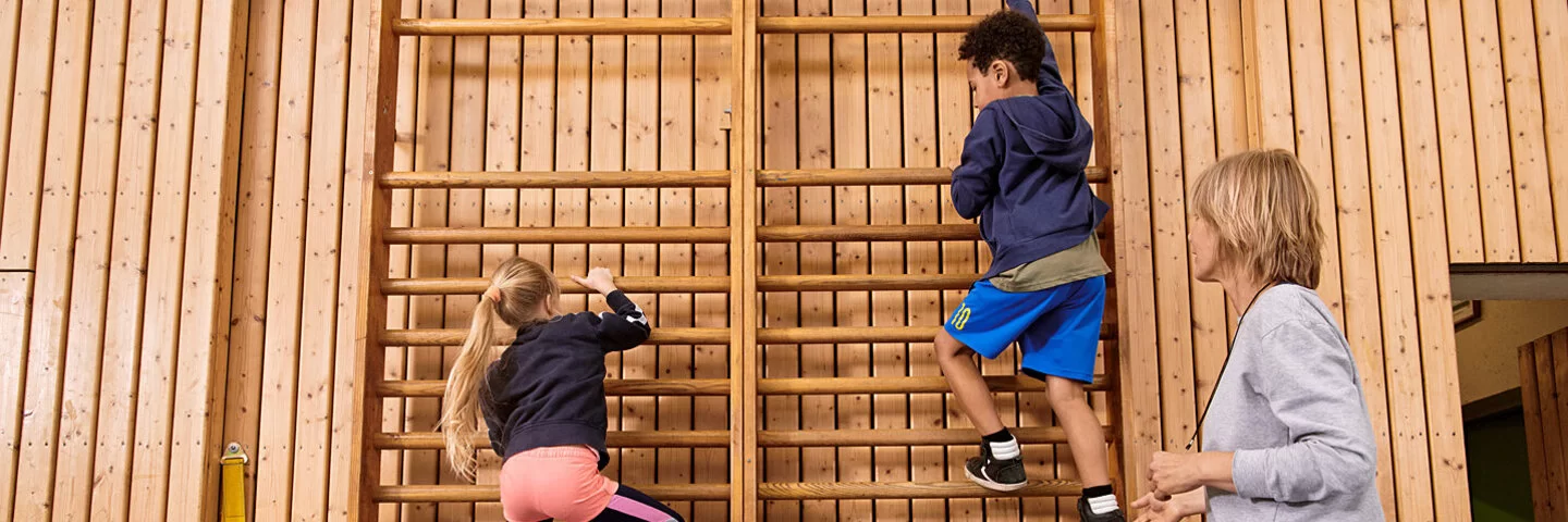 Kinder machen zusammen mit einer Lehrerin Sport. Beim Präventionsprogramm „Henrietta & Co.“ erfahren sie, warum Bewegung und gesunde Ernährung wichtig sind.