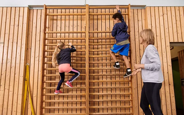 Kinder machen zusammen mit einer Lehrerin Sport. Beim Präventionsprogramm „Henrietta & Co.“ erfahren sie, warum Bewegung und gesunde Ernährung wichtig sind.