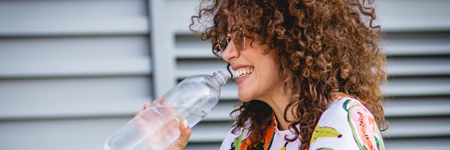 Junge Frau trinkt klares Glas Wasser.