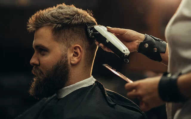 Ein Mann bekommt mit einem Haarschneidegerät den Nacken ausrasiert.