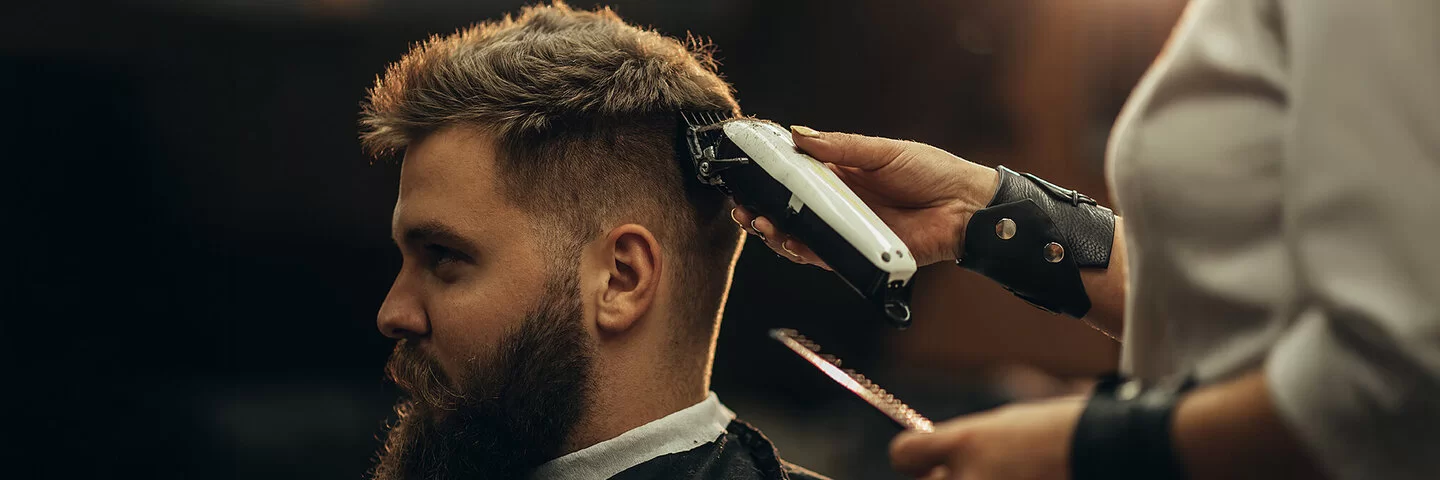 Ein Mann bekommt mit einem Haarschneidegerät den Nacken ausrasiert.