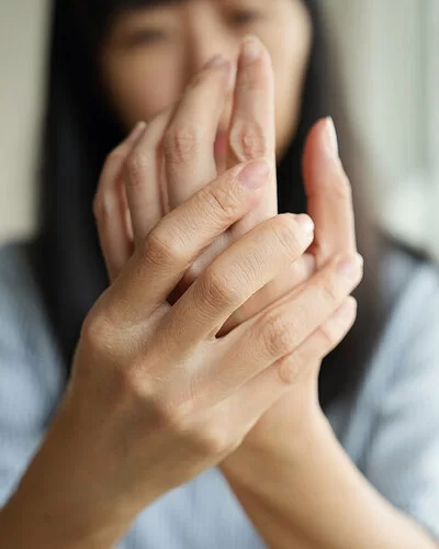 Im Vordergrund die Hände einer Frau, die sich die Innenfläche ihrer linken Hand ansieht.