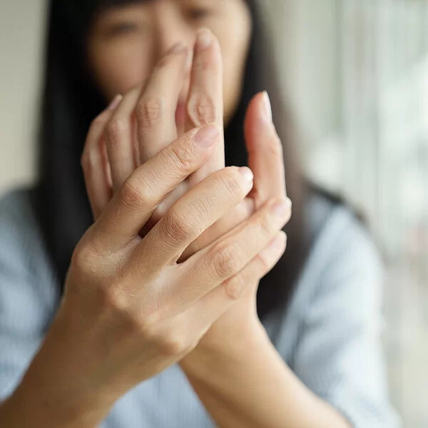 Im Vordergrund die Hände einer Frau, die sich die Innenfläche ihrer linken Hand ansieht.