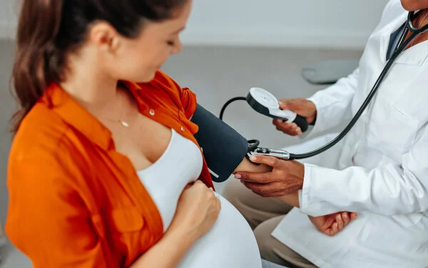 Schwangere Frau l�ässt ihren Blutdruck von einer medizinischen Fachkraft checken.