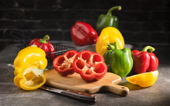 Paprika in verschiedenen Farben liegen auf einer Küchenarbeitsplatte.