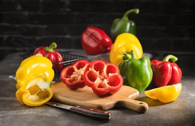 Paprika in verschiedenen Farben liegen auf einer Küchenarbeitsplatte.