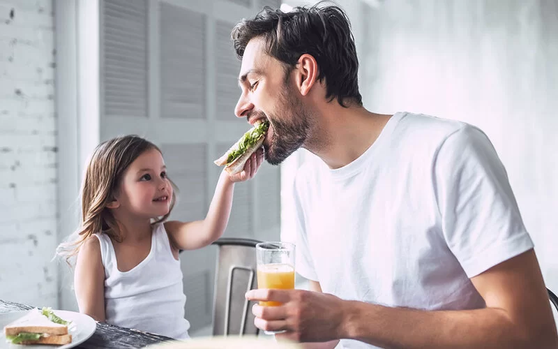 Vater lässt sich von Tochter mit gesundem Sandwich füttern