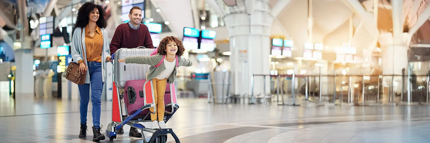 Eine junge Familie läuft mit einem Gepäcktrolley durch eine Flughafen