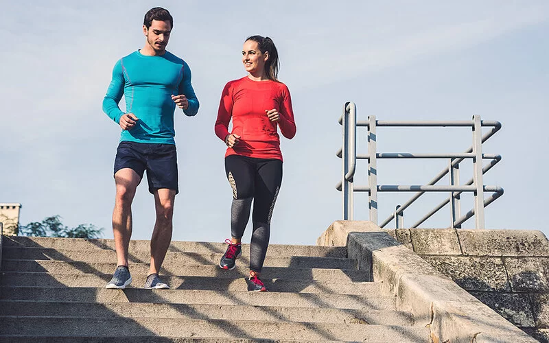 Ein Mann und eine Frau joggen eine Treppe runter.